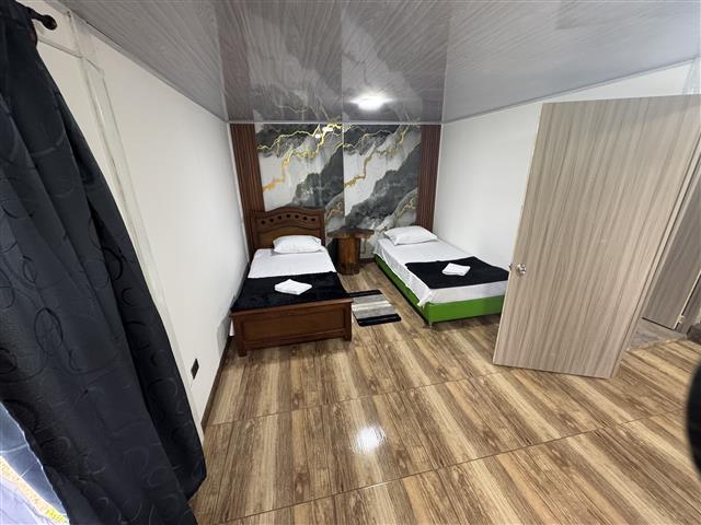 ecohotelgaia19 Alquiler Fincas Quindio Hoteles Eje Cafetero Planes Transporte Twin hotel room with two single beds white linens black throws and a marble patterned accent wall