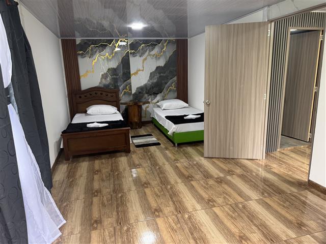 ecohotelgaia20 Alquiler Fincas Quindio Hoteles Eje Cafetero Planes Transporte Hotel room with two single beds a small nightstand between them and a marble like wall mural wood floors and an open door to the hallway