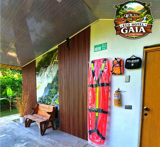 ecohotelgaia6 Alquiler Fincas Quindio Hoteles Eje Cafetero Planes Transporte Entrance area of Eco Hotel Gaia with a wooden slat wall a wooden bench and red life jackets hanging near a door with a fire extinguisher nearby